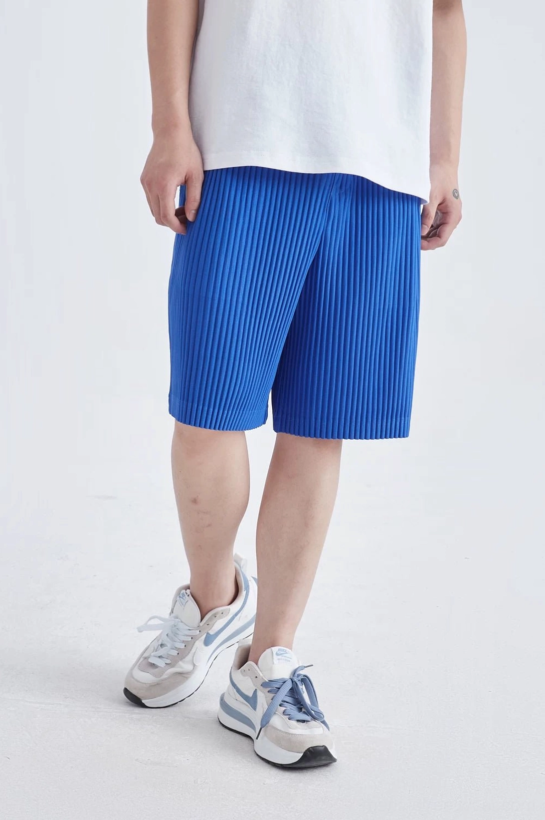 Dark gray pleated tech shorts with clean architectural texture for minimalist streetwear looks