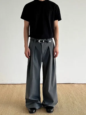 Dark gray pleated wide-leg tailored trousers worn with a black t-shirt and leather shoes in a minimalist Seoul streetwear outfit front view