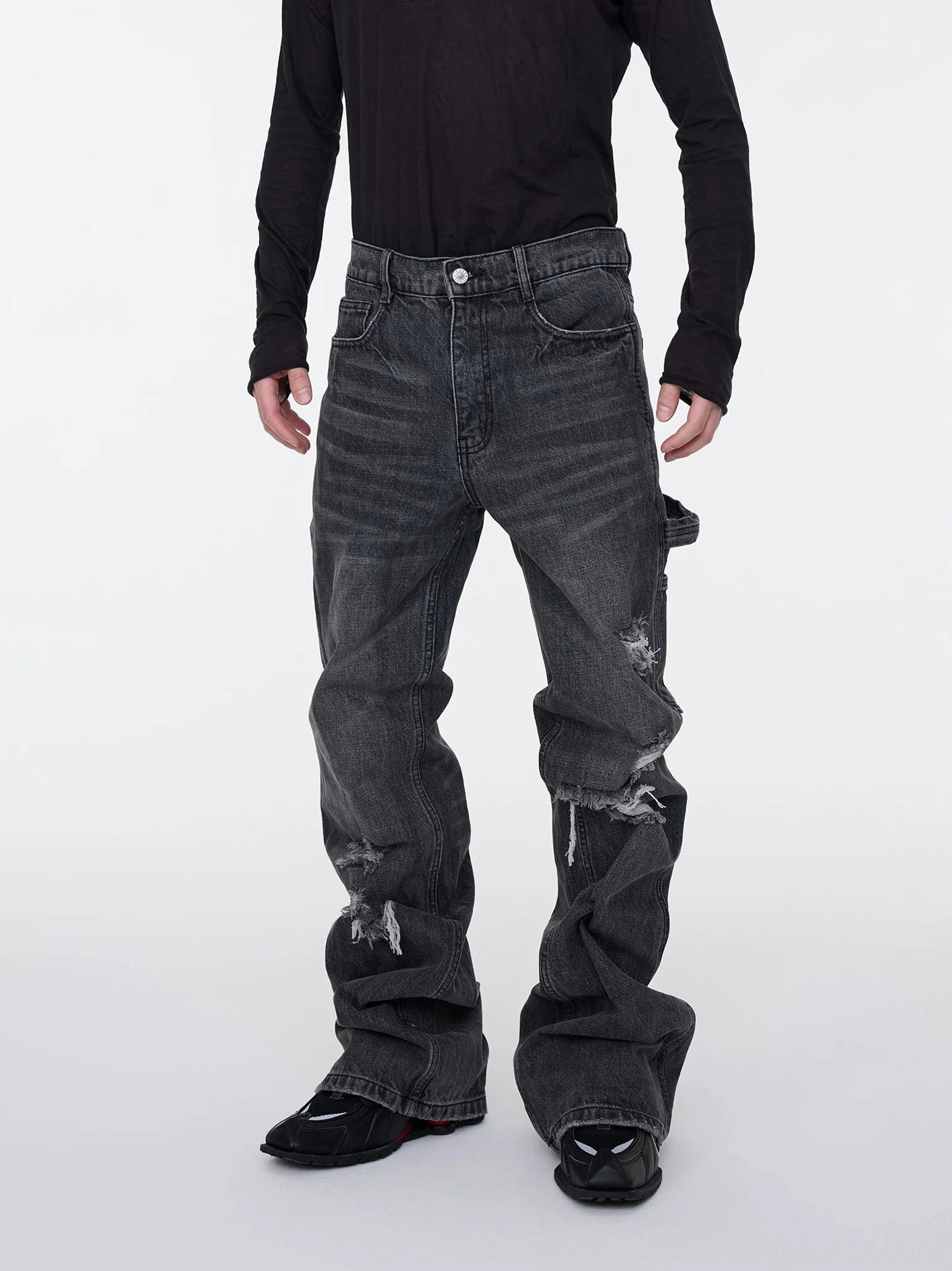 Male model in black top wearing dark gray ripped stacked flare cargo jeans with thigh knee distressing and side pocket