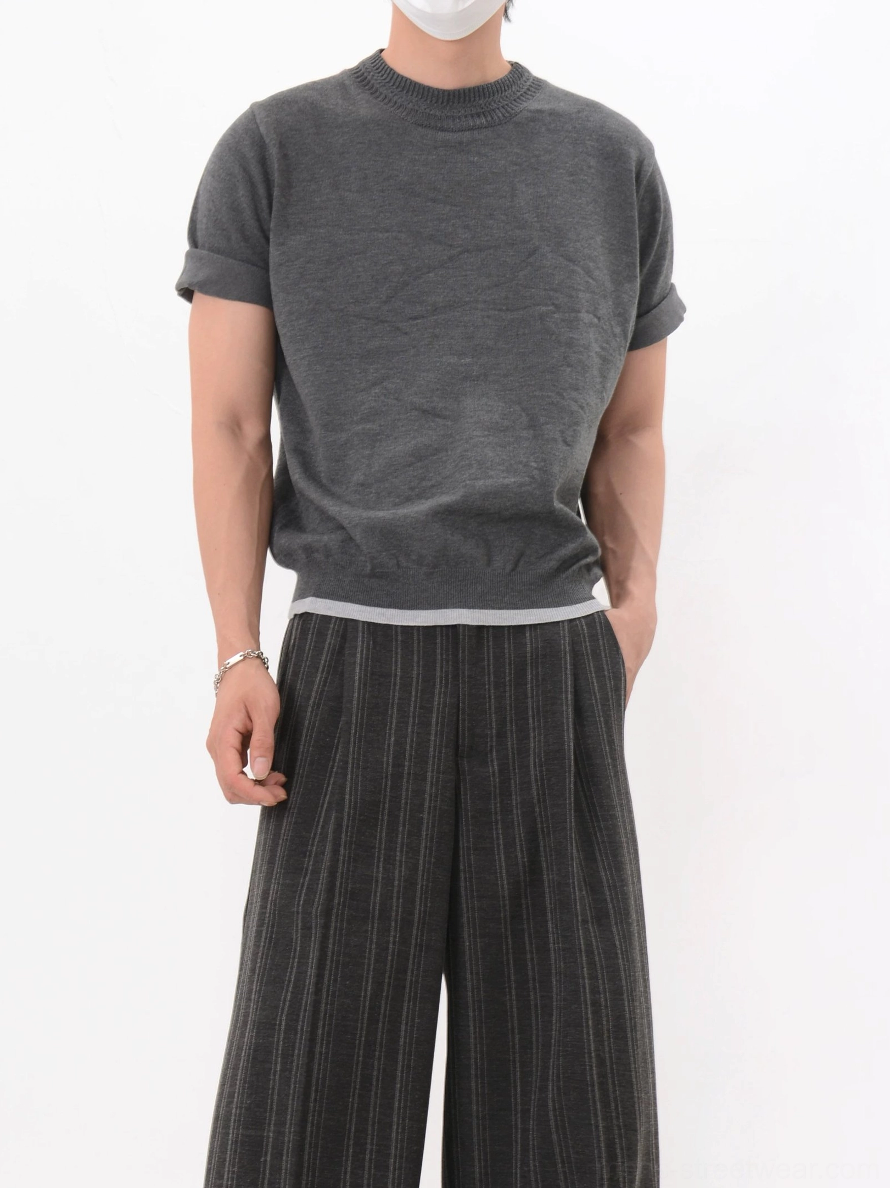 Dark gray vintage-inspired textured knit T-shirt with rolled short sleeves and contrast hem paired with pleated striped wide leg pants