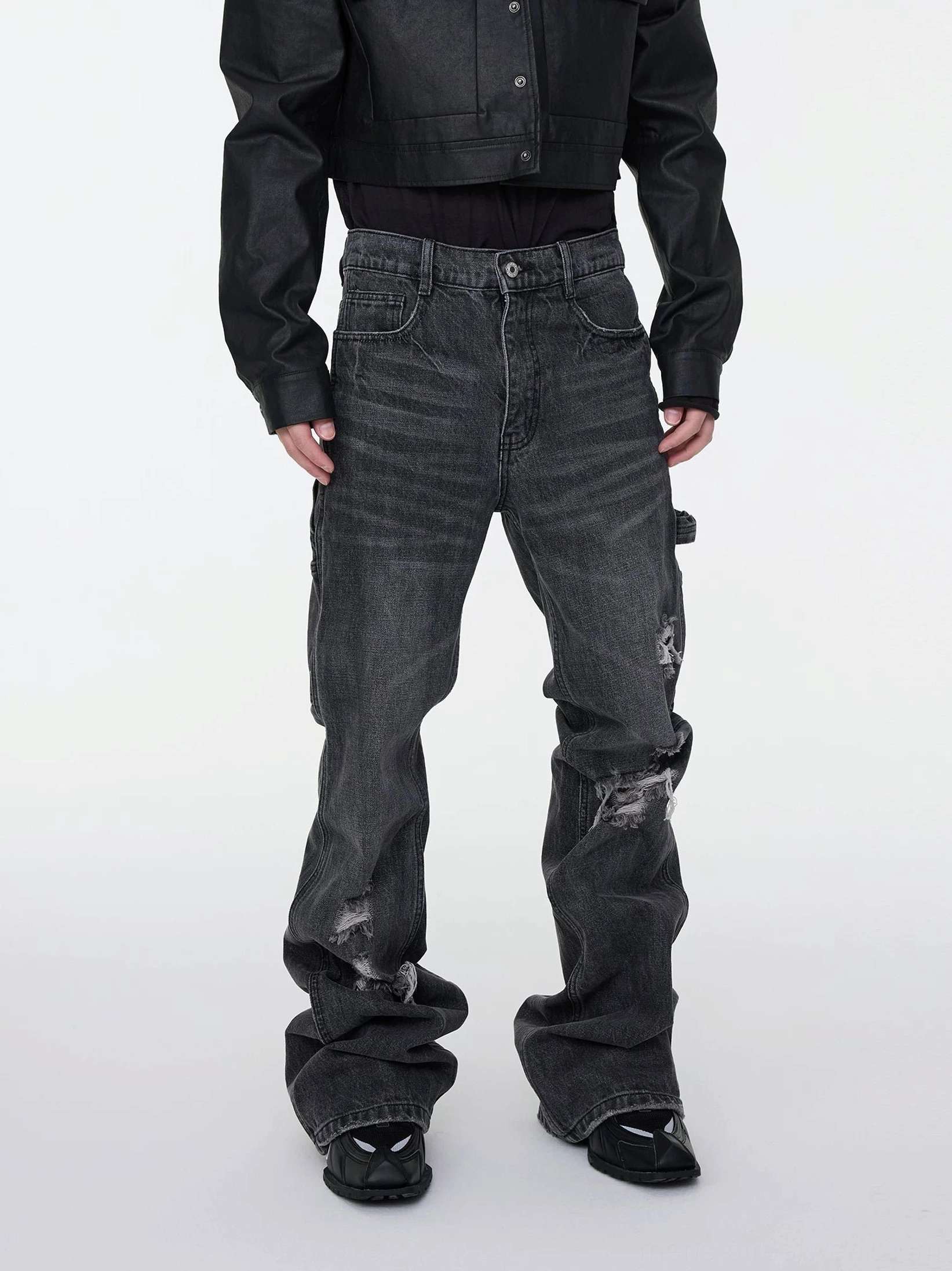 Full body front view of washed charcoal distressed stacked denim cargo jeans with faded whiskering and flared hems