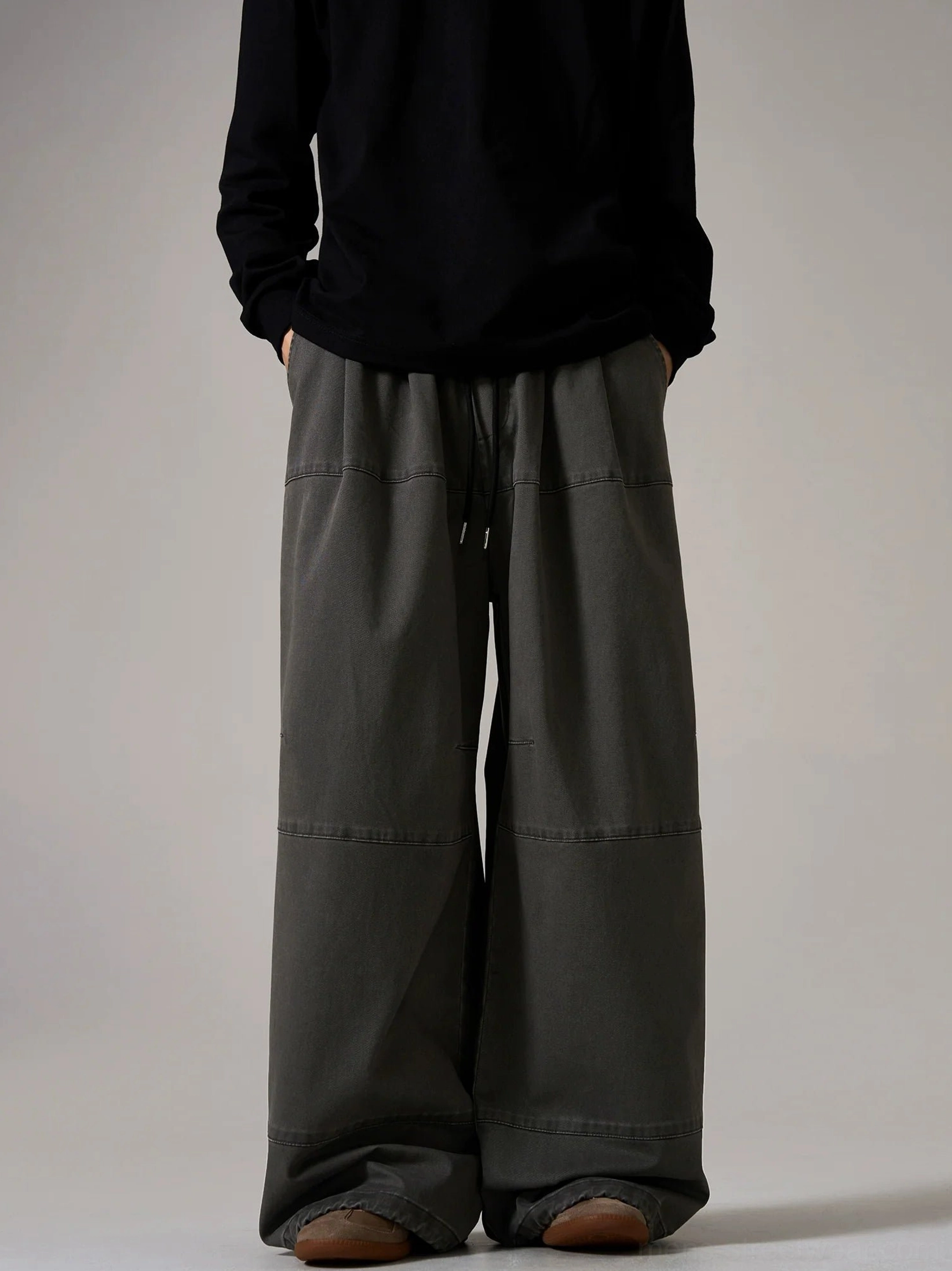 Dark gray wide cargo pants with elastic drawstring waist, ultra-wide skater fit, contrast construction seams, and modern Korean streetwear styling