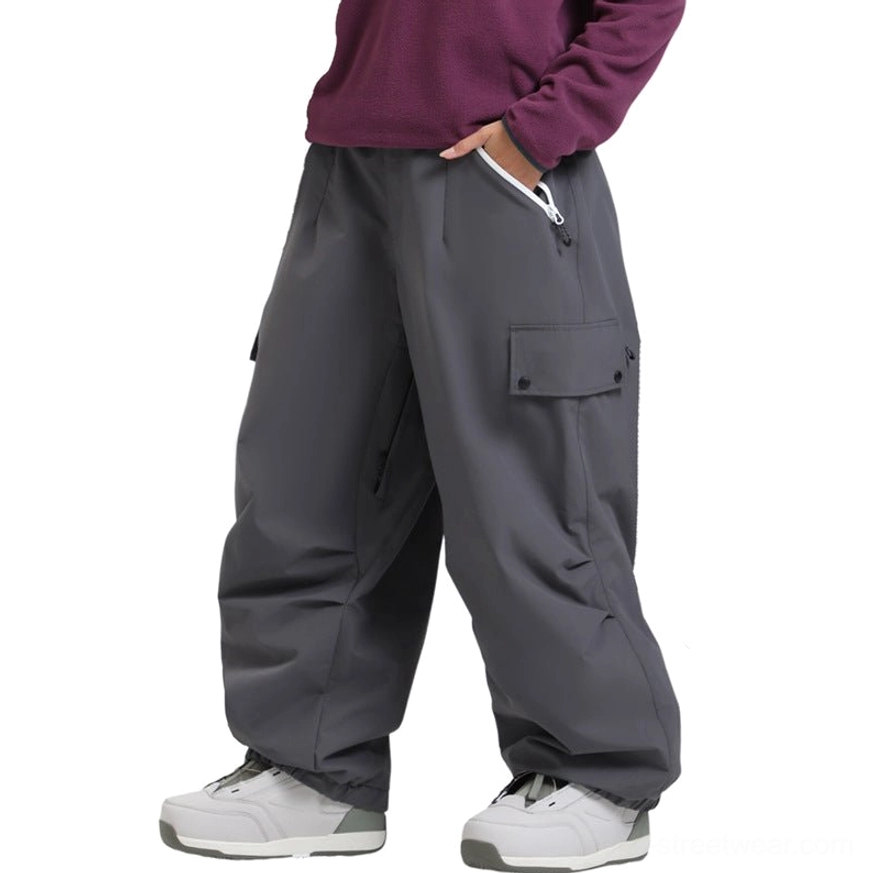 Dark gray wide-leg cargo snow pants with water-resistant fabric, side zipper pocket, thigh flap pocket, and oversized snowboard streetwear fit