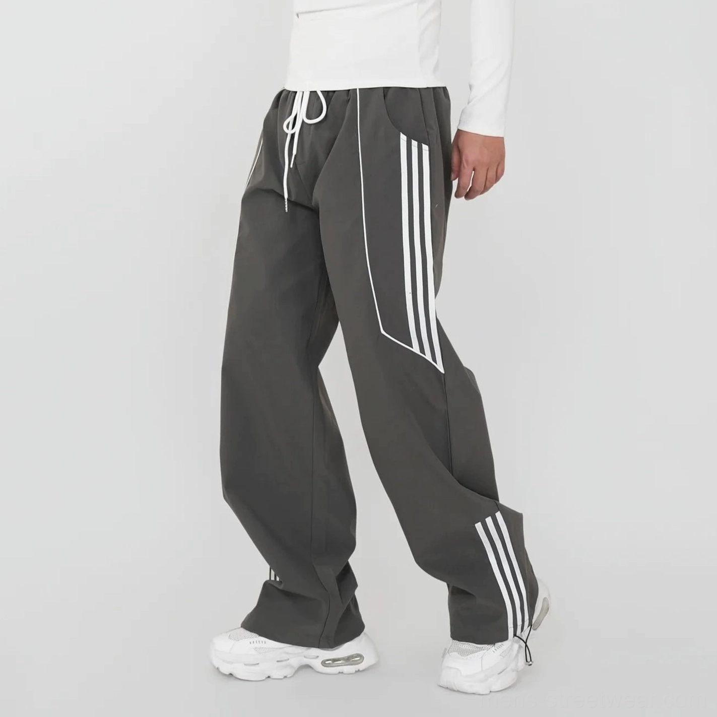 Dark gray wide-leg track pants with bold white triple side stripes, relaxed drawstring waist, and oversized East Asian streetwear styling