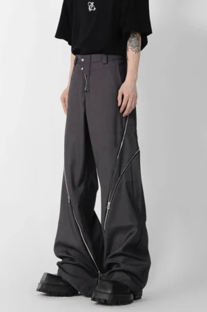 Dark grey high-waisted zipper slit trousers shown from a three-quarter angle with wide legs, outer-leg zipper details, and chunky black platform boots