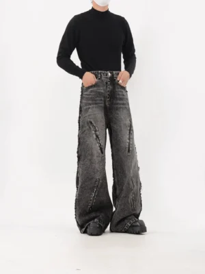 Dark grey raw-edge wide-leg streetwear jeans shown from the front with industrial zipper details and oversized silhouette