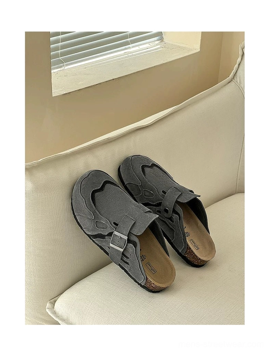 Dark grey suede buckle clogs displayed on a sofa with layered tonal panels and adjustable streetwear strap
