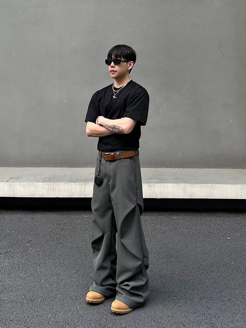 Full front view of dark grey wide-leg draped trousers styled with sunglasses, silver necklace, brown leather belt, and pendant in Seoul-inspired streetwear fashion