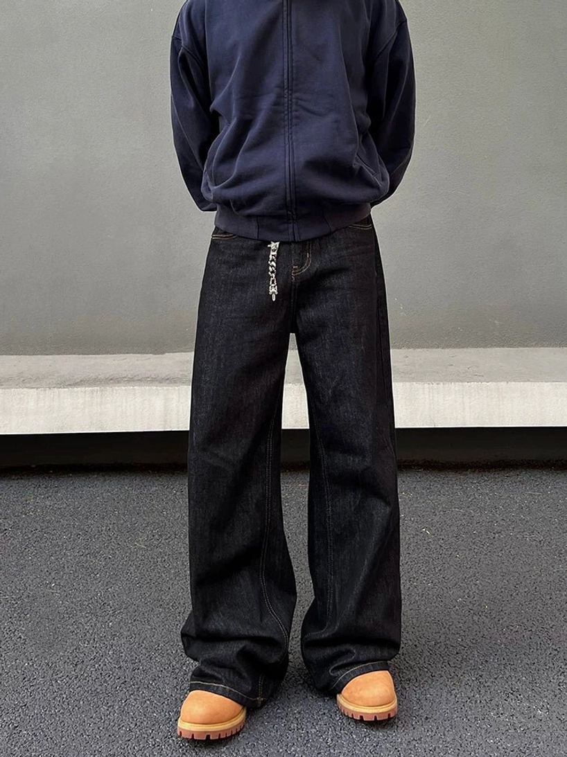 Front full-body view of dark indigo wide leg streetwear jeans with metal chain waist detail and stacked hems