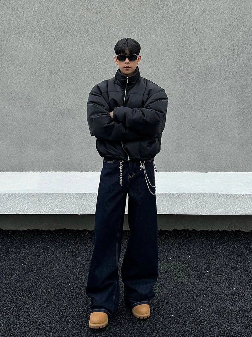 Full front outfit view featuring dark indigo loose wide-leg jeans, black puffer jacket, sunglasses, and tan boots in contemporary streetwear style