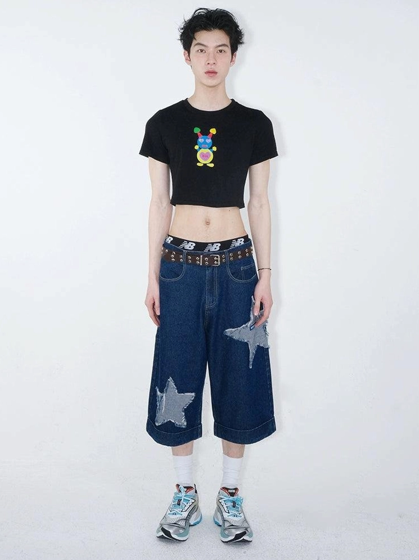 Full outfit view of dark indigo star patch denim culottes paired with a black cropped tee, brown leather belt, and sporty sneakers