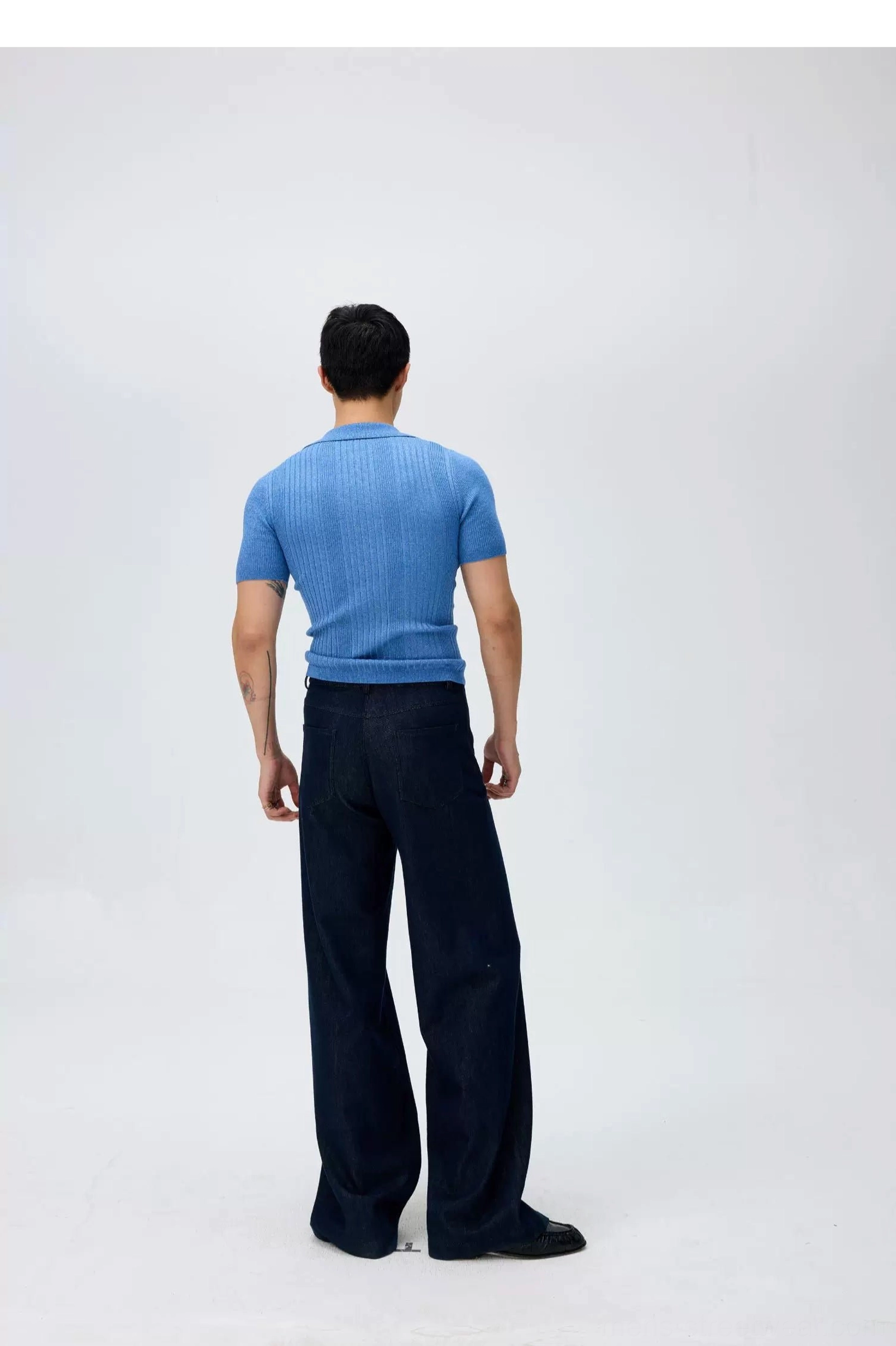 Rear view of dark indigo high-waisted wide-leg sailor denim trousers with a clean relaxed silhouette and blue ribbed knit top