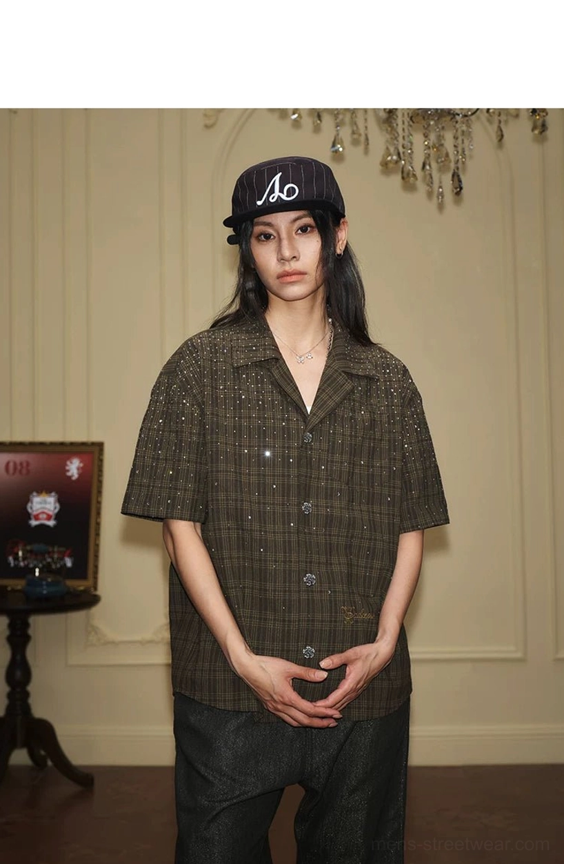Front view of a dark olive plaid rhinestone camp collar shirt with short sleeves and understated embroidered detail