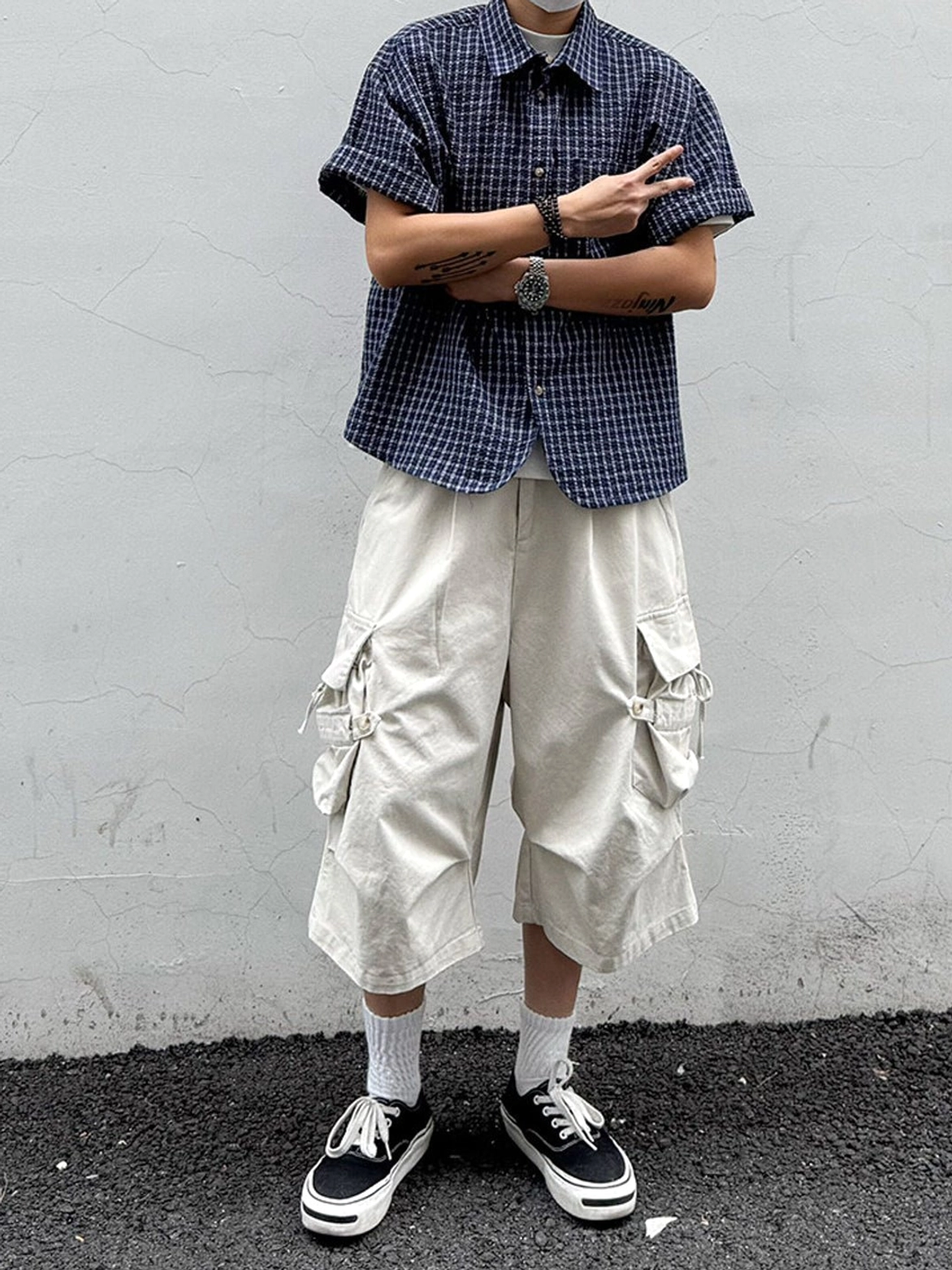 Dark plaid oversized short sleeve button shirt paired with beige cropped cargo pants and skate shoes