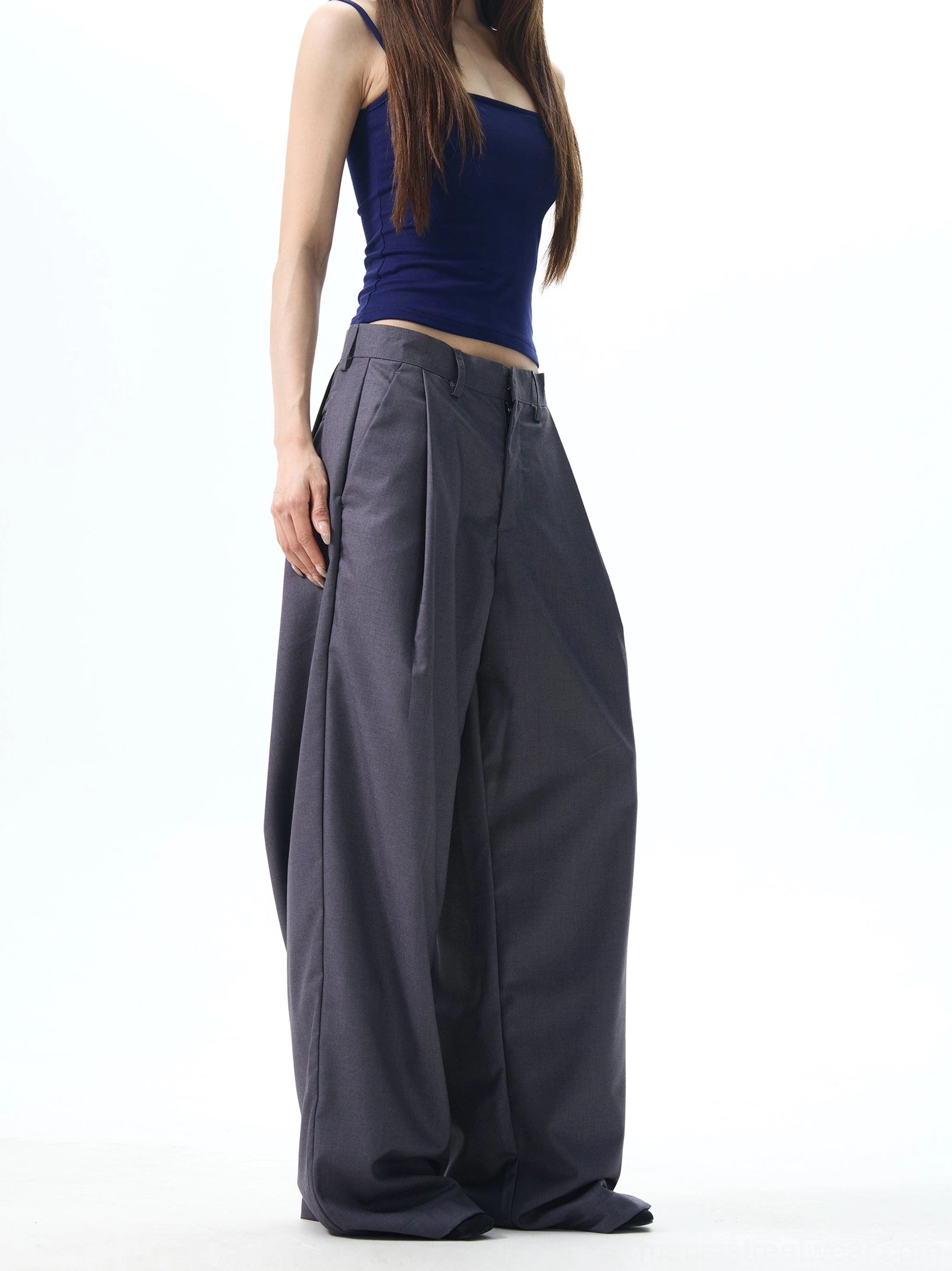 Side view of dark slate grey high waisted pleated wide leg trousers with fluid draped tailoring