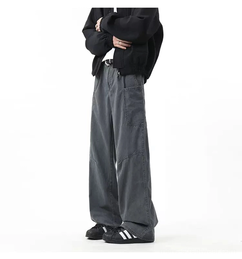 Dark slate grey utility cargo pants with relaxed wide-leg silhouette styled with a black cropped jacket and athletic sneakers