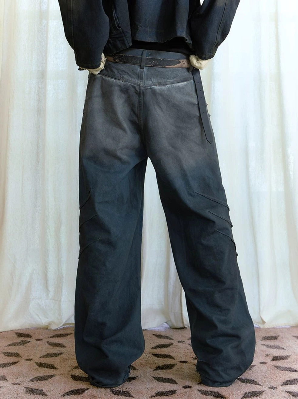 Back view of dark wash distressed stacked wide-leg jeans showing relaxed oversized fit and faded denim finish