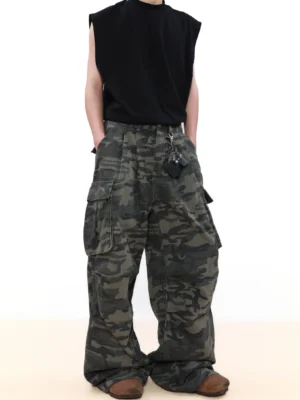 Front view of dark woodland camo wide leg cargo pants with oversized utility pockets, styled with a black sleeveless top and brown boots