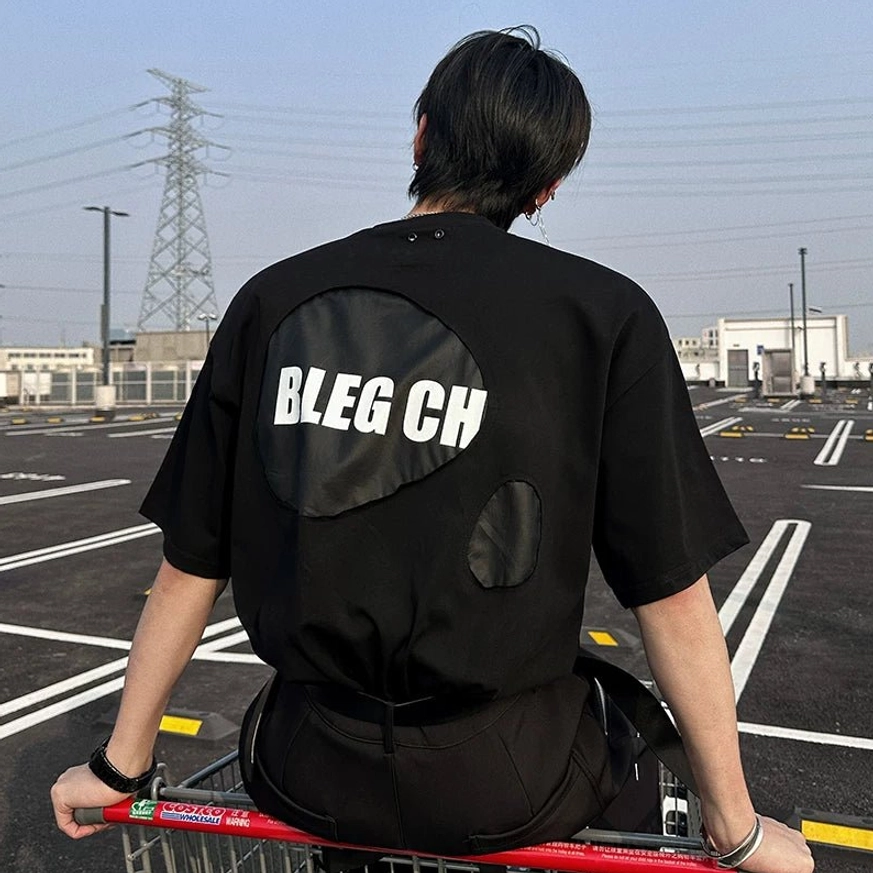 Black deconstructed oversized street tee with subtle chest patch and bold contrast back graphic panel