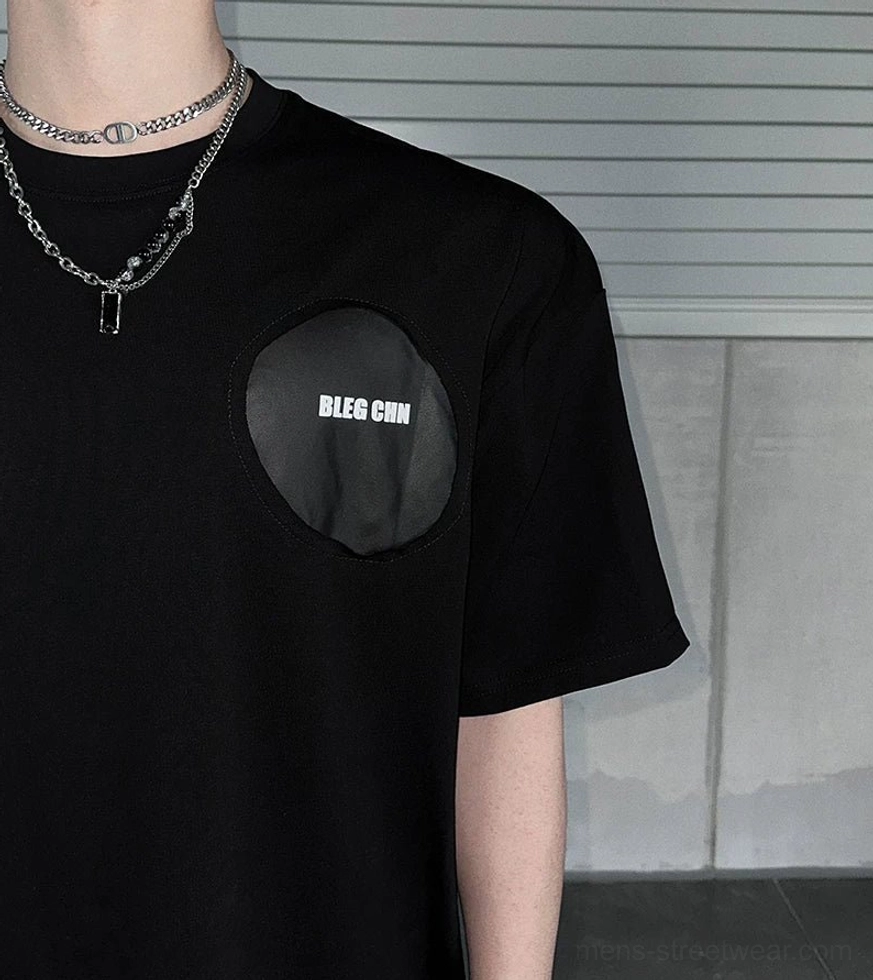 Close-up front view of soft black cotton blend oversized street tee with circular tonal chest patch