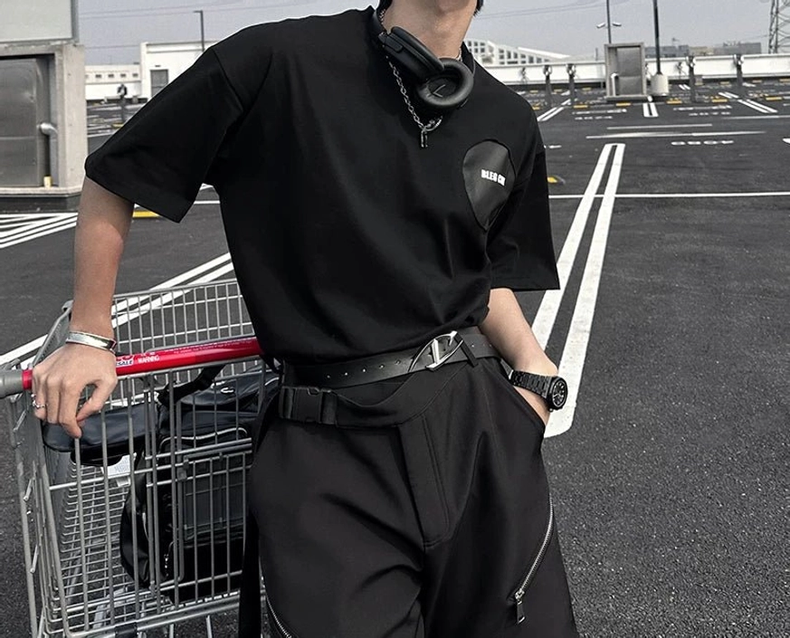 Front torso view of deconstructed oversized black street tee with chest patch and relaxed short sleeves