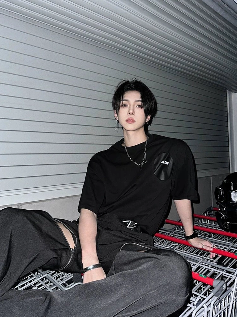 Loose fit black streetwear tee with minimal chest patch and dropped shoulders styled with wide-leg trousers