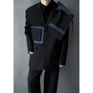 Close-up of men's black asymmetric cargo blazer featuring envelope utility pockets, notched lapels, and indigo denim contrast details