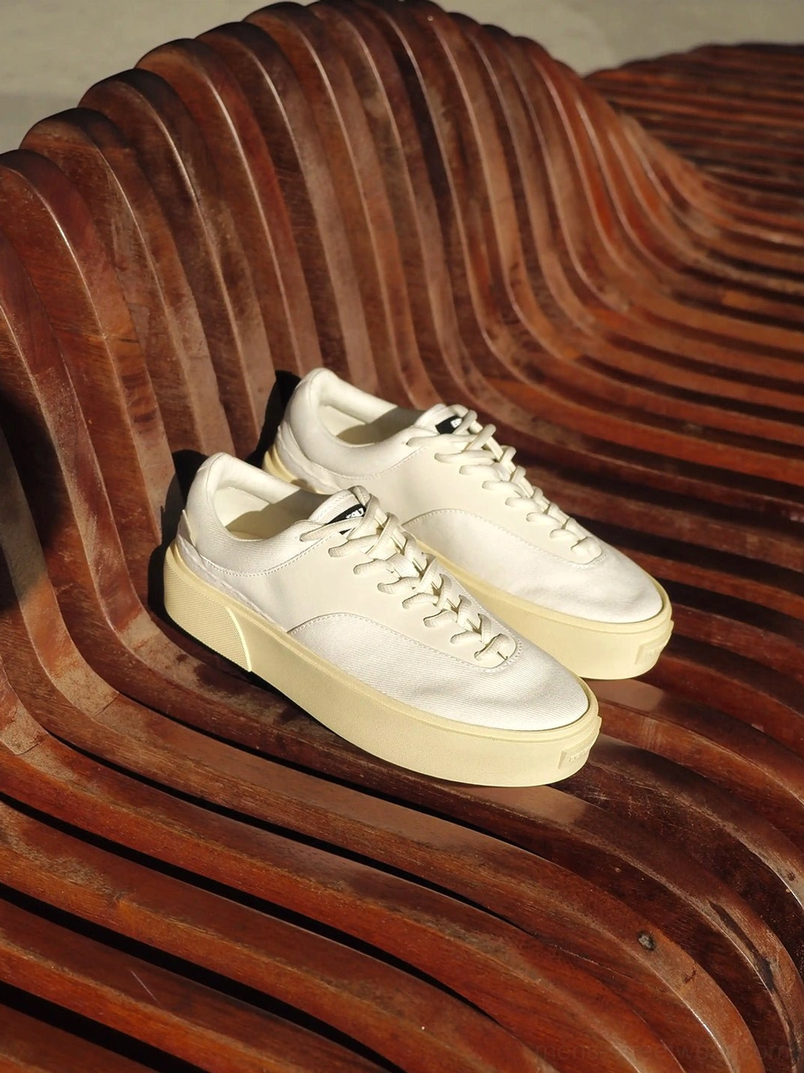 Desert Gray low-top canvas platform sneakers placed on a wooden outdoor bench with cream soles