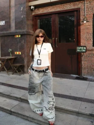 Faded desert wash wide leg jeans with black music note graffiti print and red star hem details front view