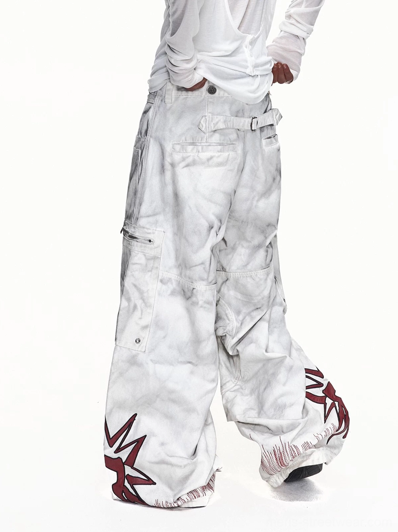 Rear model view of off-white washed wide-leg cargo pants showing adjustable back waist belt, frayed hems, and red star leg graphics
