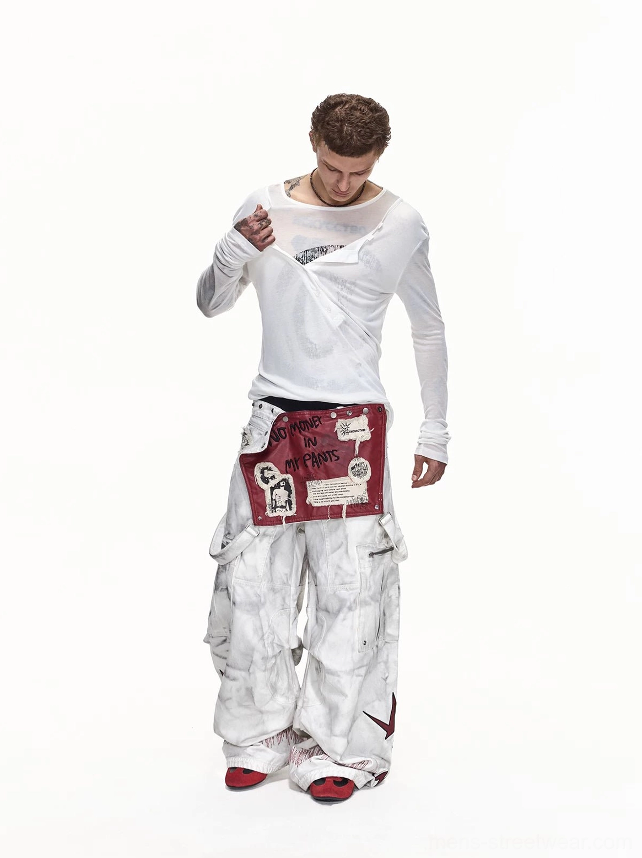 Male model styling detachable red apron washed wide-leg cargo pants with a white long-sleeve shirt in a minimalist studio