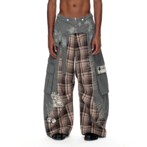 Front close-up of washed grey and brown plaid detachable waist cargo pants with wide legs, oversized side pockets, embroidered graphics, distressed stitch details, and black leather shoes