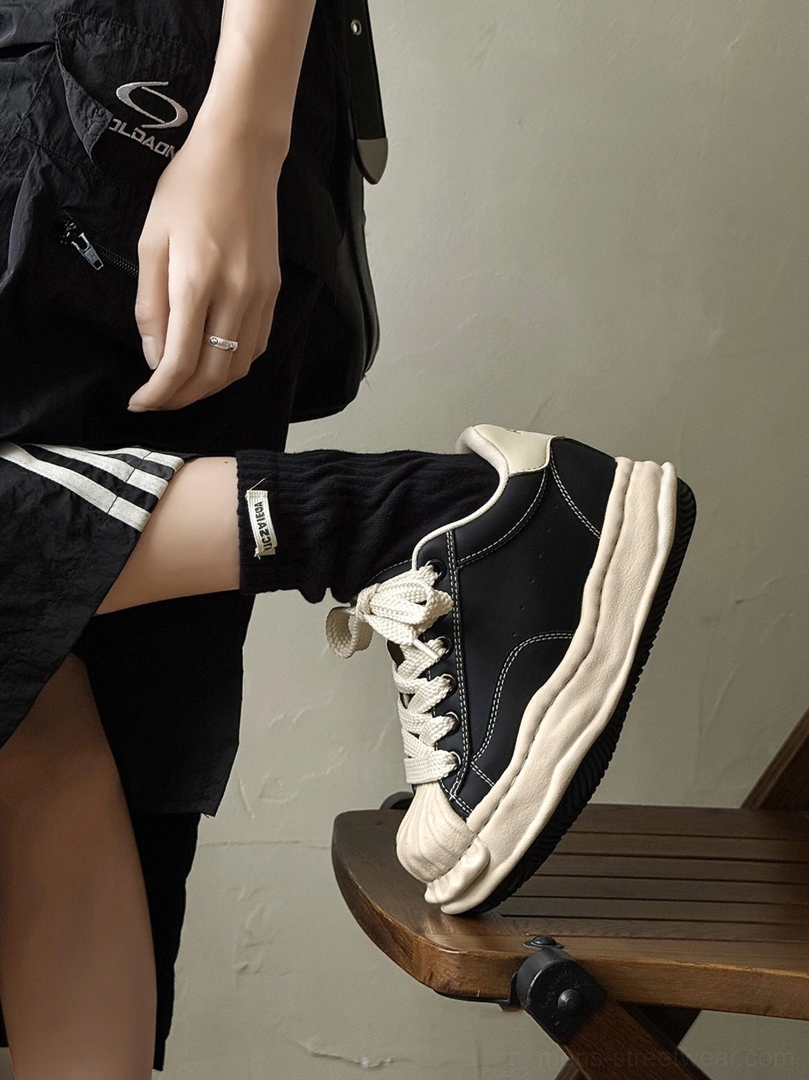 Close-up side profile of a distressed black platform court sneaker showing cream toe detail and aged-style sole trim