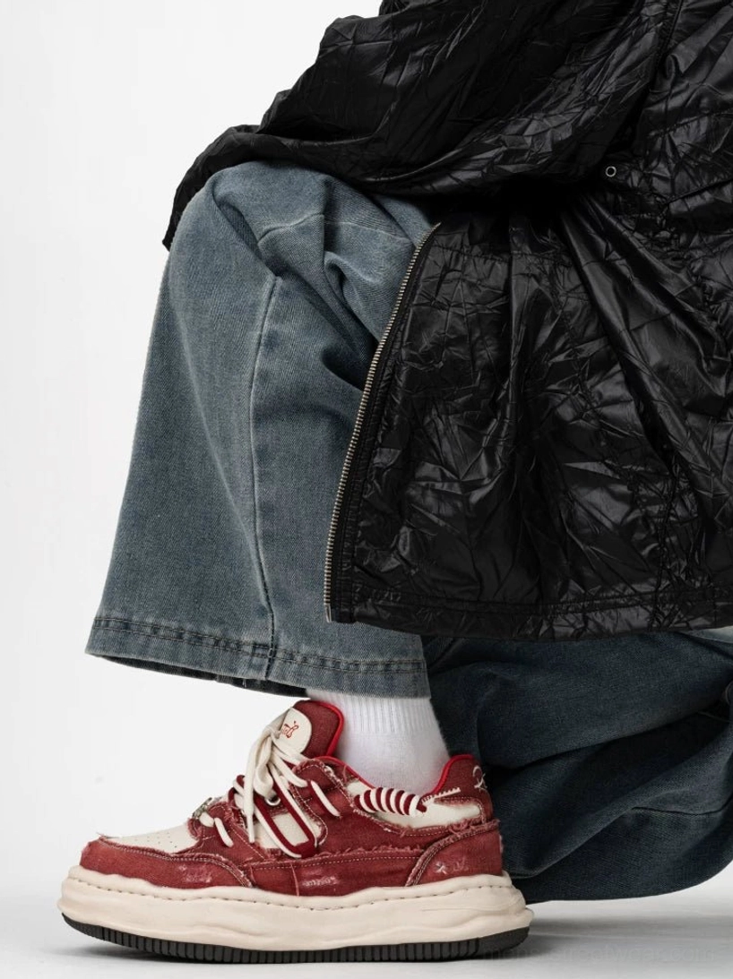 Red and white distressed skate-inspired platform sneaker worn on foot with wide-leg jeans and white socks