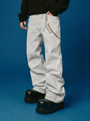 Full front view of faded white distressed wide-leg jeans styled with black chunky platform shoes, a black knit sweater, and decorative waist chain