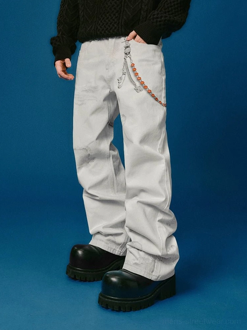 Full front view of faded white distressed wide-leg jeans styled with black chunky platform shoes, a black knit sweater, and decorative waist chain