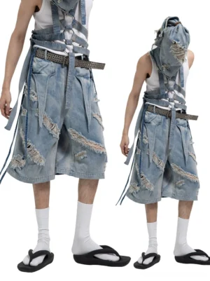 Front and back view of faded blue distressed denim harness Bermuda shorts with frayed rips, wide waist belt, and trailing straps