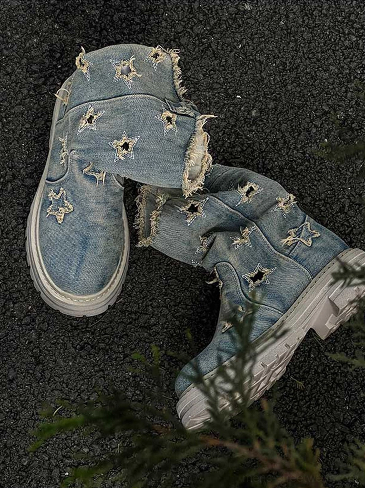 Overhead flat lay of a pair of washed denim distressed star cutout platform boots showing frayed openings and rugged outsoles