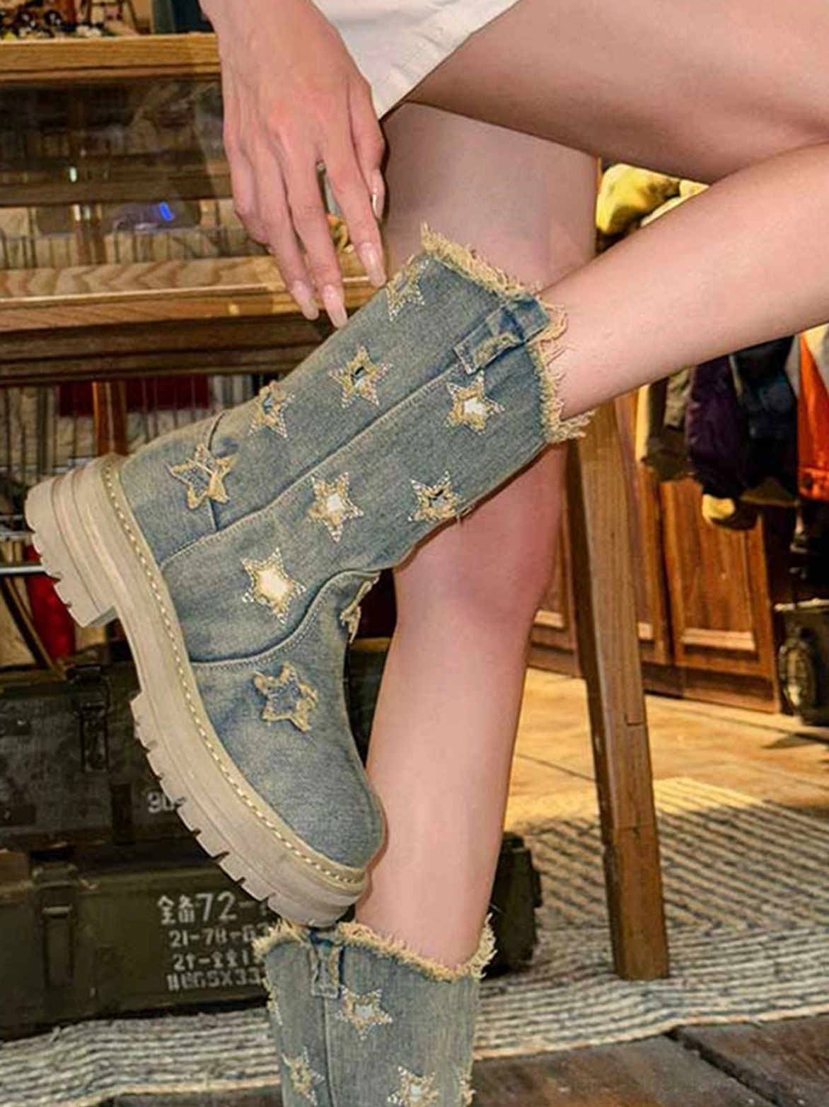 Close-up side detail of washed denim star motif platform boot with frayed shaft edge and chunky treaded rubber sole
