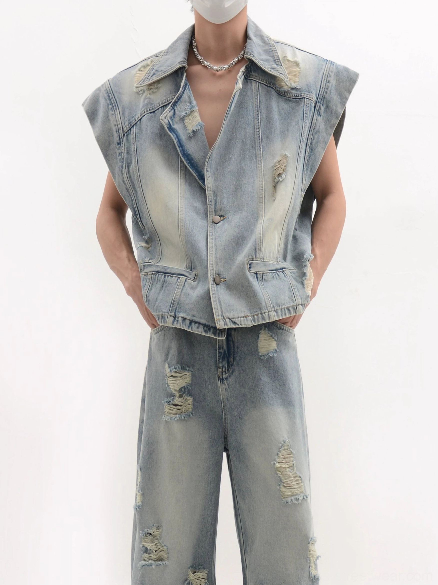 Close waist-up detail of a distressed denim vest showing flap pockets, faded cotton texture and frayed streetwear finishes