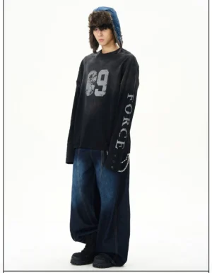 Three-quarter view of black oversized distressed Force graphic long sleeve streetwear tee styled with a trapper hat, wide-leg denim, work boots, and cuff chain detail