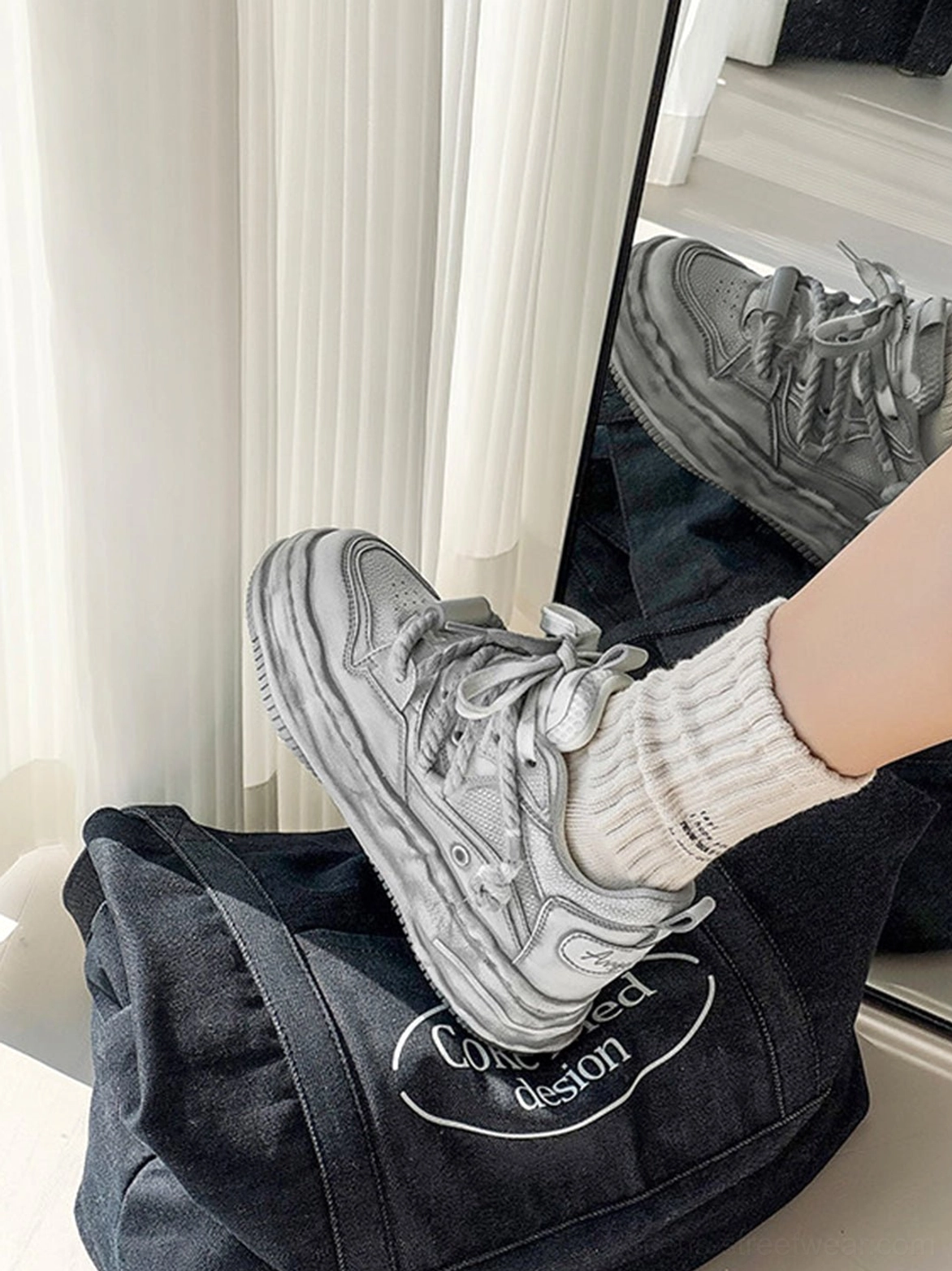 Close-up overhead view of distressed gray platform sneakers styled with beige socks and a dark denim tote bag
