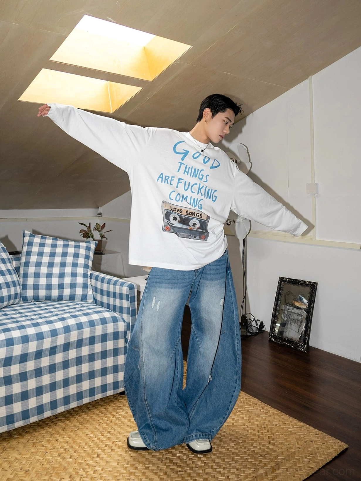 Casual indoor outfit showing oversized blue balloon leg jeans with faded distressed denim wash and graphic long sleeve top