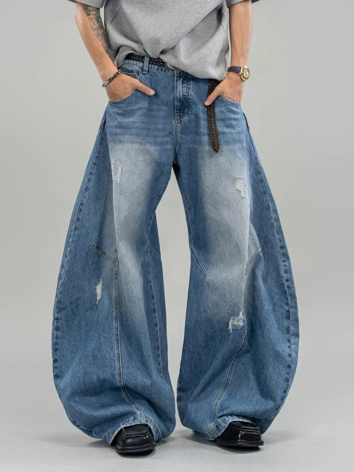Close-up full-leg view of blue distressed balloon leg jeans with exaggerated wide silhouette and faded indigo finish