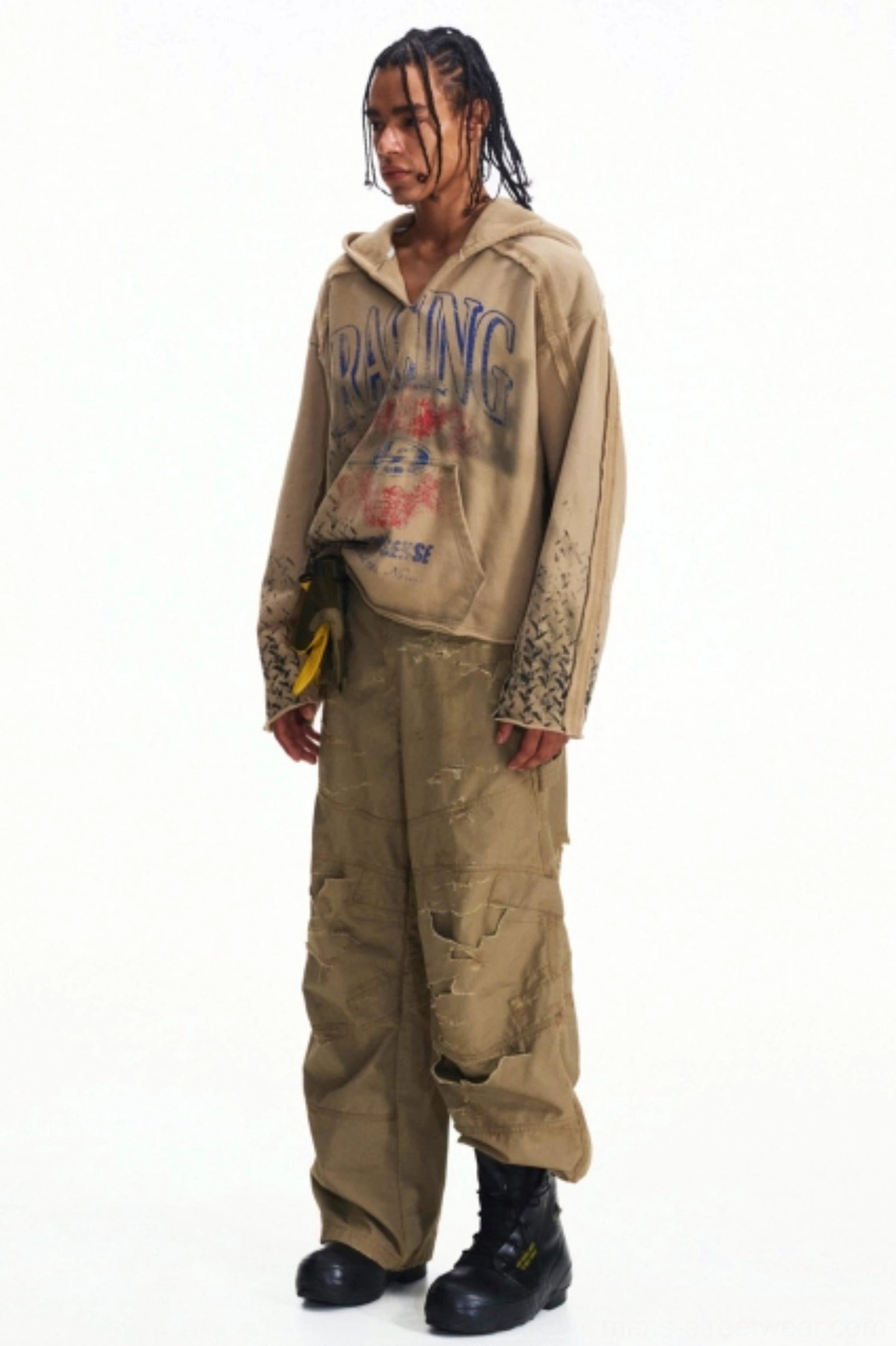 Side full-body view of distressed khaki utility cargo pants styled with a faded hoodie and black combat boots in a vintage streetwear look