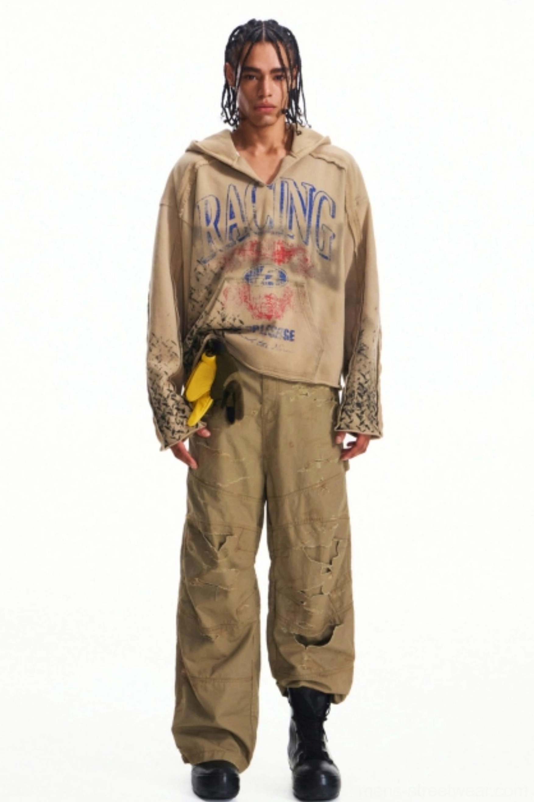 Full-body vintage streetwear outfit with distressed khaki cargo pants, faded racing graphic hoodie, yellow waist accessory, and black combat boots
