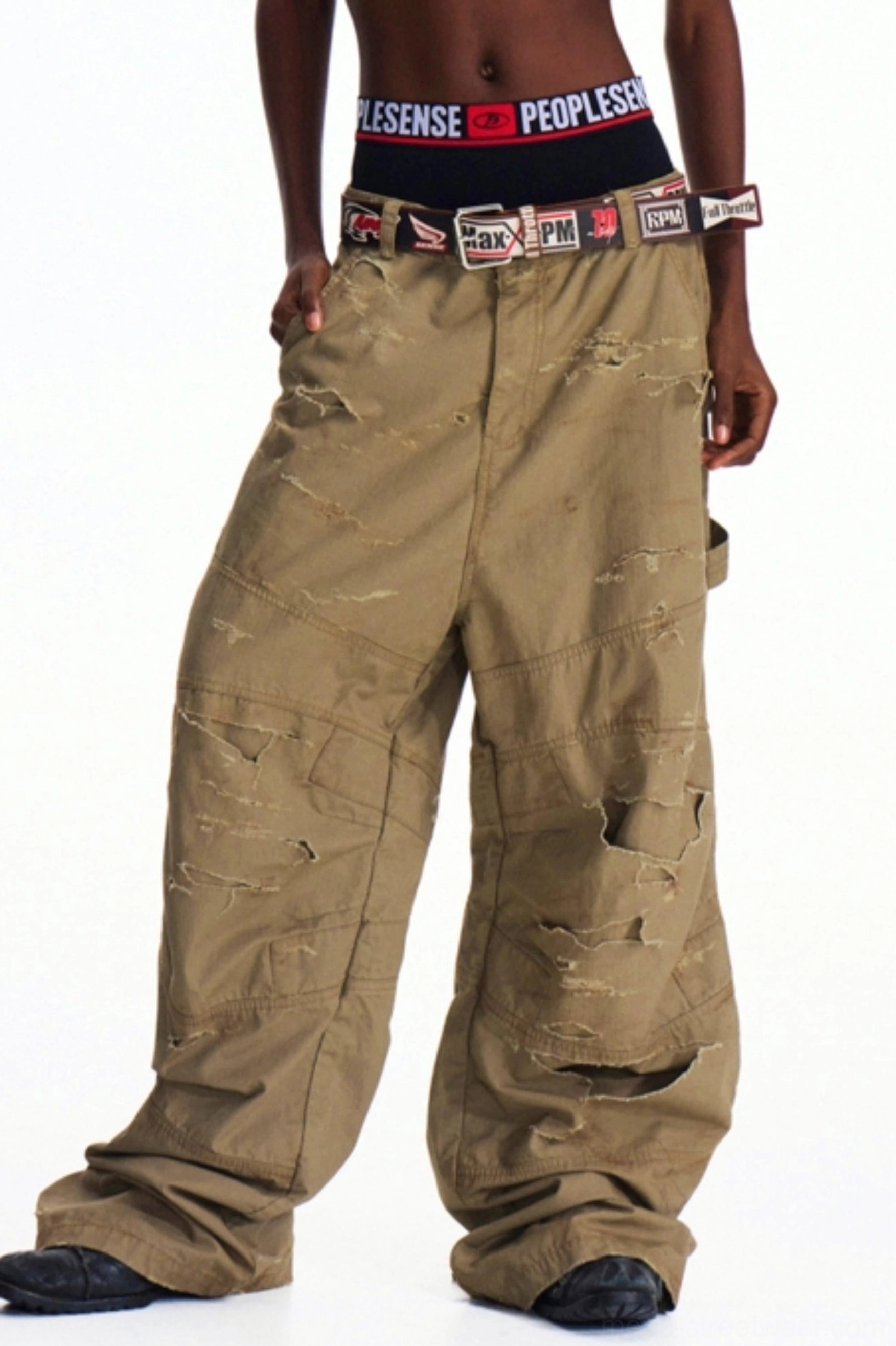 Distressed khaki wide-leg utility cargo pants shown in left three-quarter view with oversized side pockets and frayed streetwear detailing