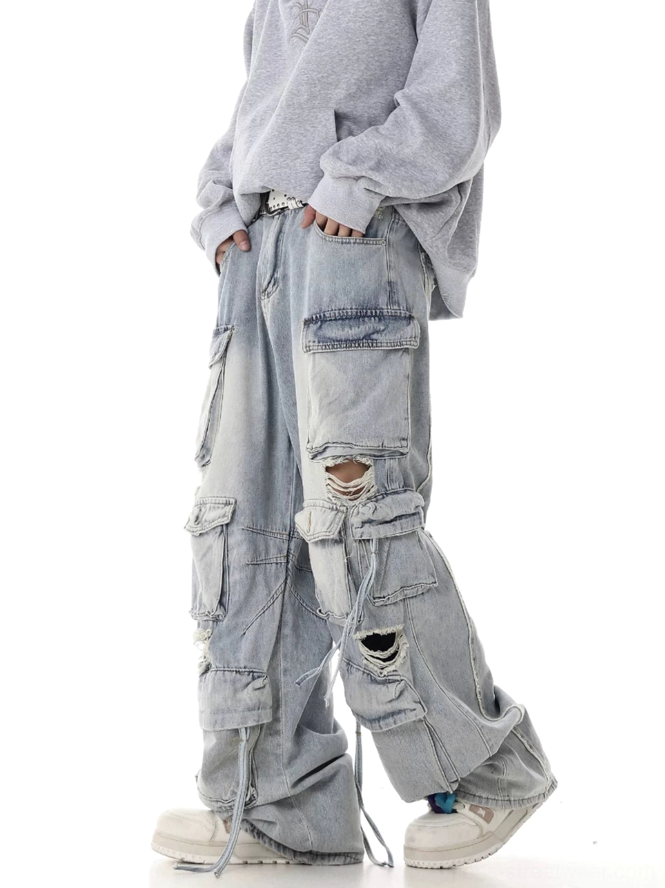 Light blue baggy cargo jeans side view showing layered utility pockets distressed knees and long drawstring hem