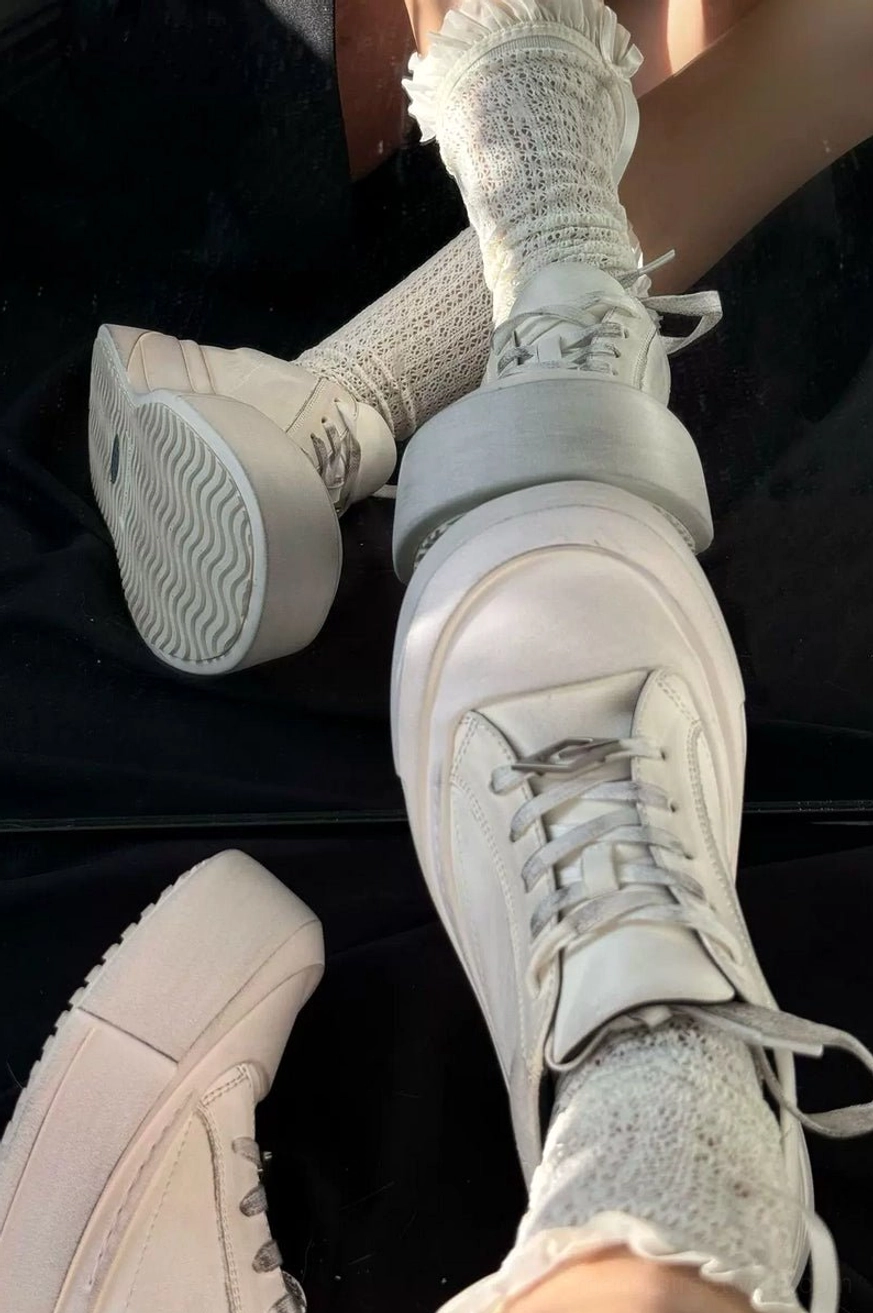 Model wearing distressed off-white leather toe cap platform sneakers with textured crew socks and elevated light-colored sole
