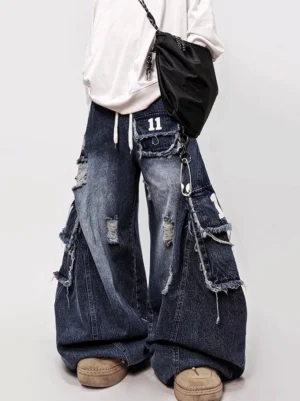 Front full-length view of dark blue distressed cargo wide-leg jeans featuring drawstring waist, layered patch pockets, metal chain detail, and oversized streetwear fit